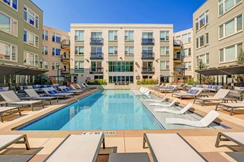 a swimming pool with lounge chairs in front of an apartment building